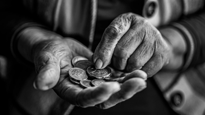 black and white photo of aged hands holding coins